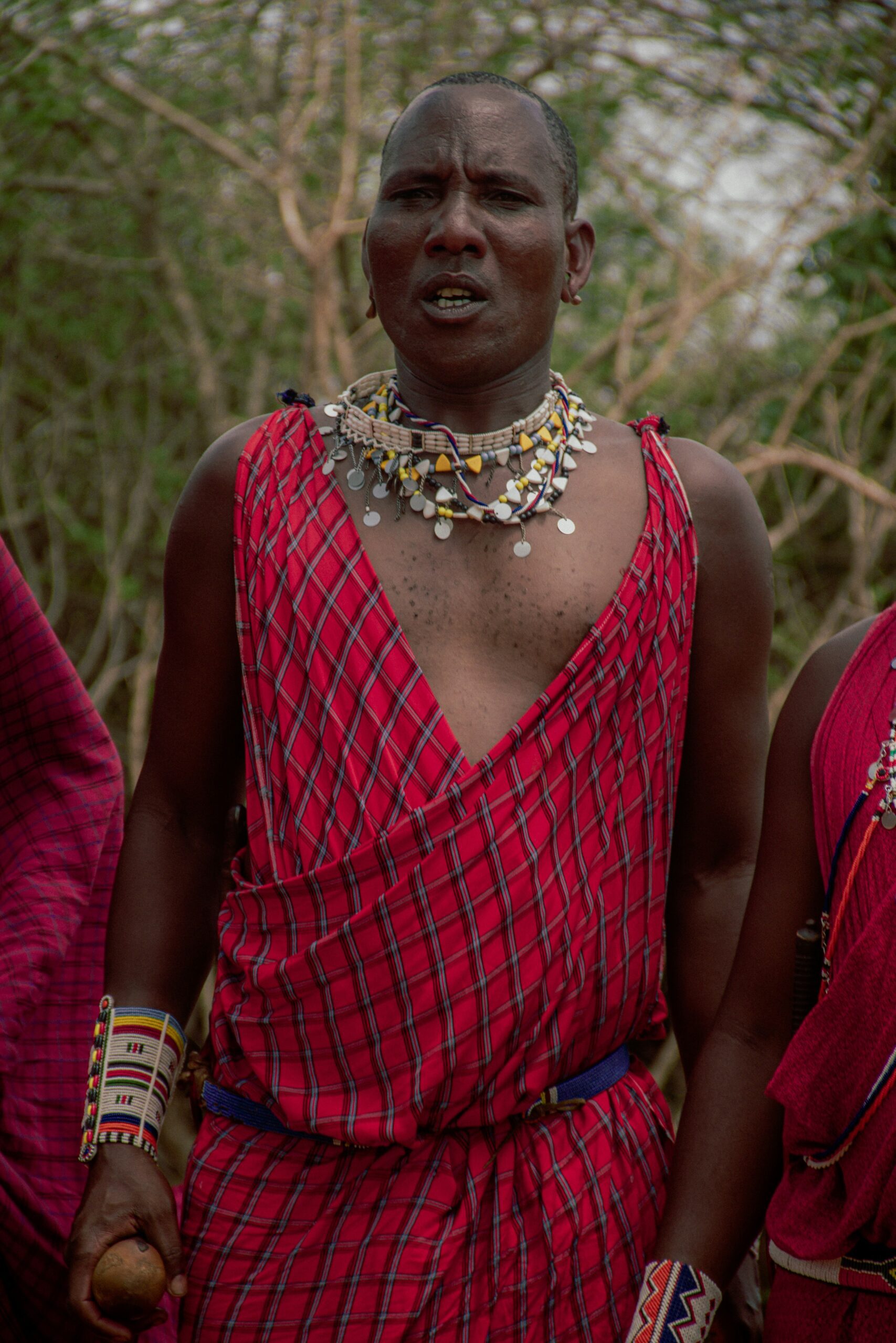 Maasai man in red and black plaid dress wearing silver necklace